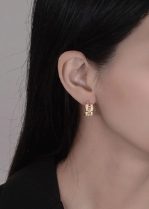 Macro shot of 925 silver 18k gold earrings with wavy links and pink zircon stones