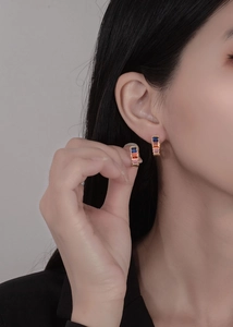 Detail of colorful zircon hoop earrings on model featuring gradient rainbow crystals
