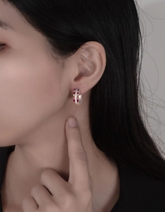 Detail of pavé hoop earrings with colorful gemstones and white zircon on model's ear