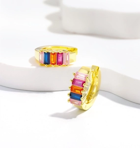 Détail de boucles d'oreilles huggies dorées avec cinq zircons rectangulaires multicolores