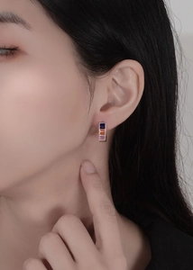 Macro side view of silver S925 earrings with blue, orange and purple square-cut zircons