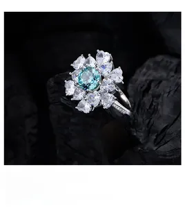 Makroaufnahme von 925 Silberring in Blumenform mit blauem Stein auf Holzkohle