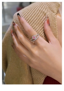 Gros plan d'une bague diamant rose en cœur avec anneau argenté double sur le doigt