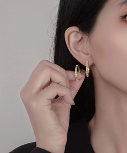 Dettaglio degli orecchini a cerchio placcati oro 18k con zirconi colorati sul modello