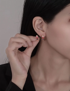 Gros plan de boucles d'oreilles créoles dorées avec zircons rectangulaires colorés sur un modèle