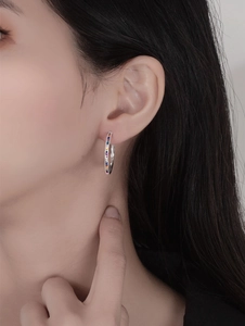 Primo piano di una modella con orecchini a cerchio in argento e gemme color arcobaleno