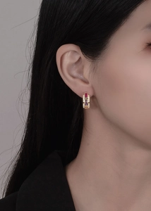 Detail of 18k gold earrings with colorful rectangular gemstones and pave side diamonds