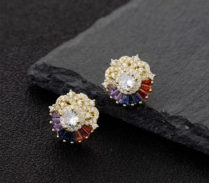 Detailed macro view of gold-tone floral stud earrings with rainbow zircon stones