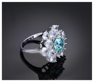 Makroaufnahme von 8mm Paraiba blauem Edelsteinring mit Birnen-Halo auf schwarzem Spiegel