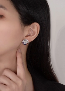 Close-up of a silver cloud earring with rainbow zircons worn on a model's ear