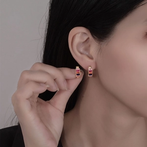 Boucles d'oreilles créoles dorées avec cristaux colorés sur le lobe d'une femme