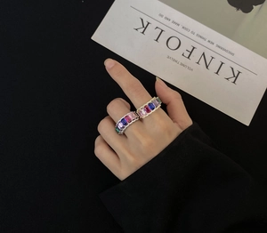 Macro detail of two silver eternity rings featuring rainbow baguette-cut colorful gemstones
