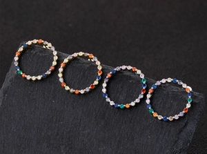 Close-up of circular earrings with multi-colored crystals on a natural stone base