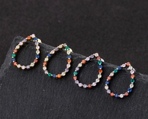Macro view of teardrop earrings with multi-colored pavé stones on black stone