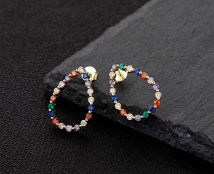 Macro detail of teardrop stud earrings featuring S925 hallmark and colorful zircon pavé