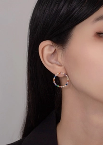 Close-up of model wearing rainbow crystal hoop earrings in gold plated finish