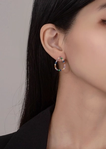 Detailed view of teardrop rainbow multi-gemstone stud earrings worn on the ear