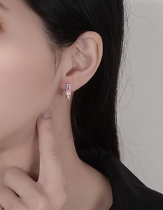 Detail of silver U-shaped hoop earring featuring a gradient of rainbow square-cut gems
