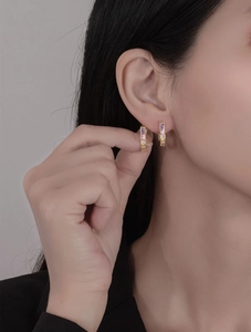 Close-up of 18k gold plated U-shaped hoop earrings with colorful rainbow zircons on ear