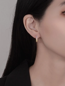 Close-up of a model wearing a gold U-shaped earring set with rainbow-colored gemstones