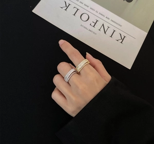 Detailed view of layered pave set rings in gold and silver finishes on a hand model