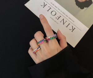 Close-up of hand wearing stacked gold rings set with colorful cubic zirconia stones