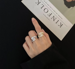 Close-up of layered S925 silver rings with baguette and pavé set diamonds on a model hand