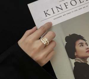 Close-up of golden bypass ring featuring parallel baguette-cut stones and pave accents