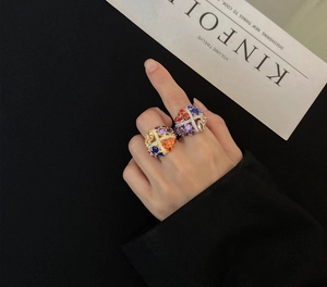 Macro detail of colorful rhinestone encrusted crossover rings in gold and silver finish