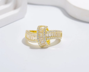 Macro detail of wavy gold-plated silver ring with baguette and round zircon inlay
