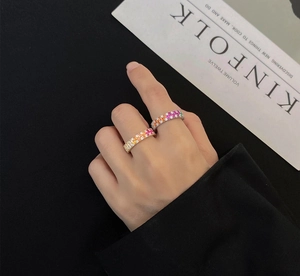 Close-up of rainbow zircon rings in gold and silver finish worn by a model on black