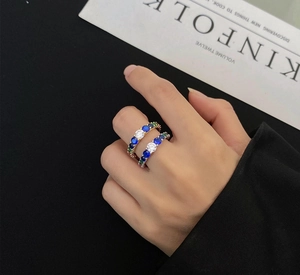 Close-up of S925 silver rings with colorful cubic zirconia worn on a hand over a magazine