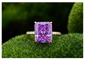 Détail macro d'une bague avec gemme violette taille radiant sur mousse naturelle
