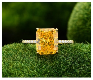 Gros plan d'une bague avec gemme jaune coupe radiante et anneau serti de diamants