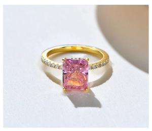 Macro detail of a radiant cut pink gemstone ring with golden band and side stones