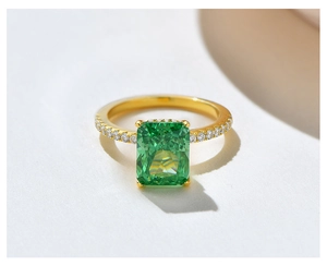 Detail of a radiant cut emerald gemstone set in a gold-plated micro-pave ring band