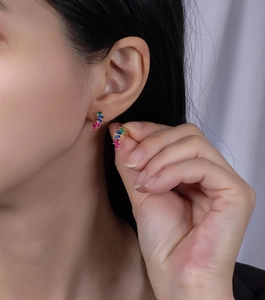 Detail of leaf-shaped earring with red, blue, and green zircons on gold plating