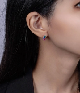 Macro shot of silver leaf earrings with vibrant green, blue, and pink colorful gemstones