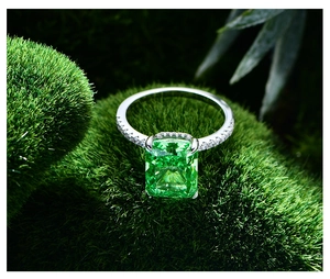 Détail macro d'une bague émeraude sur mousse montrant l'anneau pavé de diamants fins
