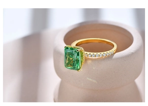 Macro shot of an emerald-cut green gemstone ring with white zircon pave in gold plating