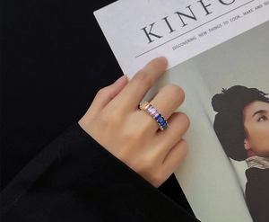 Close-up of a gold ring with rainbow baguette-cut zircons worn in a lifestyle setting