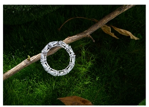 Macro shot of 925 silver eternity ring with pear-cut diamonds on a natural mossy branch