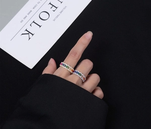 Detail of hand wearing rainbow zircon rings set with intricate gold and silver plating