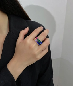 Close-up of stacked colorful baguette cut zircon rings on a model in black attire