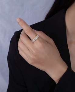 Dettaglio di un anello dorato multistrato con pietre baguette e pavé di diamanti al dito