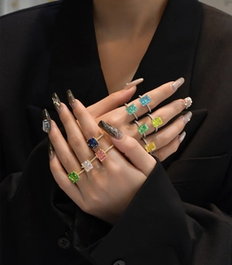 Close-up of assorted cushion-cut colorful gemstone rings with pavé set bands on a model