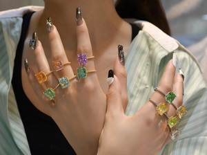 Vue détaillée de bagues colorées taille émeraude avec pavé de diamants sur main