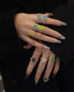 Detail of nine vibrant square-cut gemstone rings with pavé bands on a black background