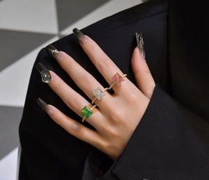 Three radiant cut gemstone rings in green white and pink with pavé gold bands on hand