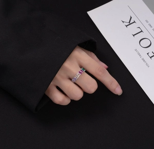 Detail of colorful emerald-cut gemstones stacked on a silver ring band shown on model